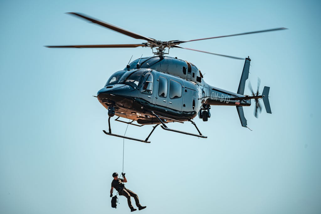 A man skillfully descends from a helicopter during a rescue operation in clear skies.
