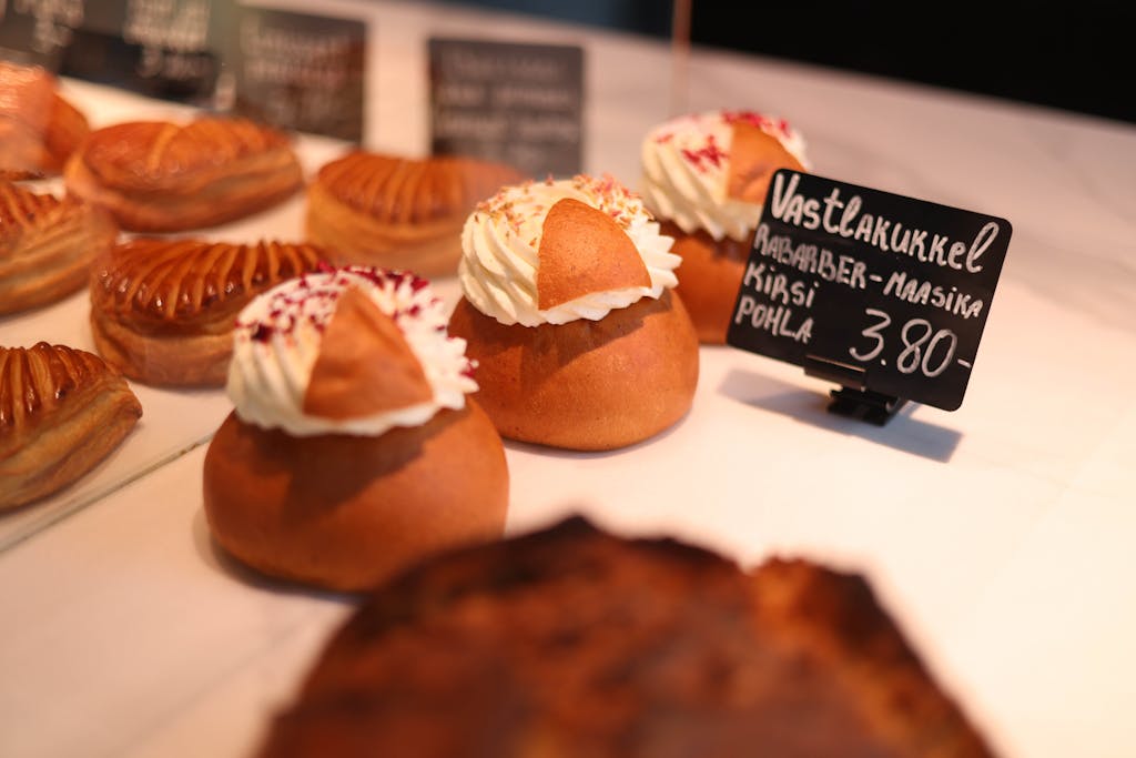 Appetizing pastries with cream and toppings, displayed in a bakery setting.