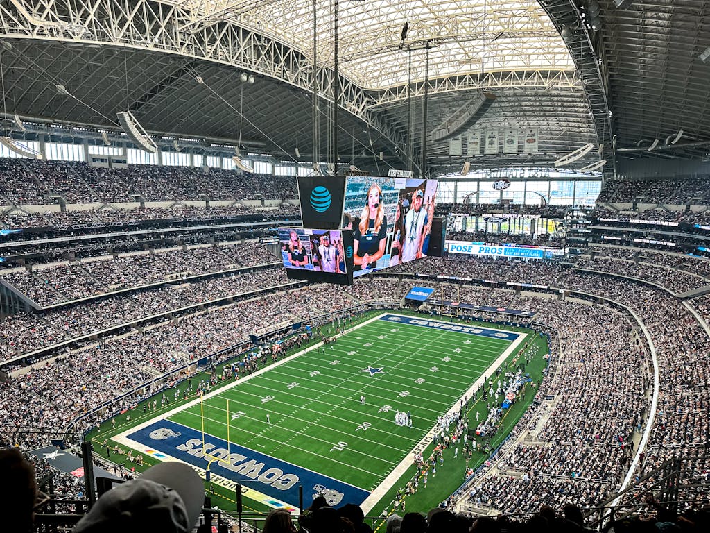 A packed AT&T Stadium in Dallas Texas, showcasing a thrilling football game with enthusiastic fans.