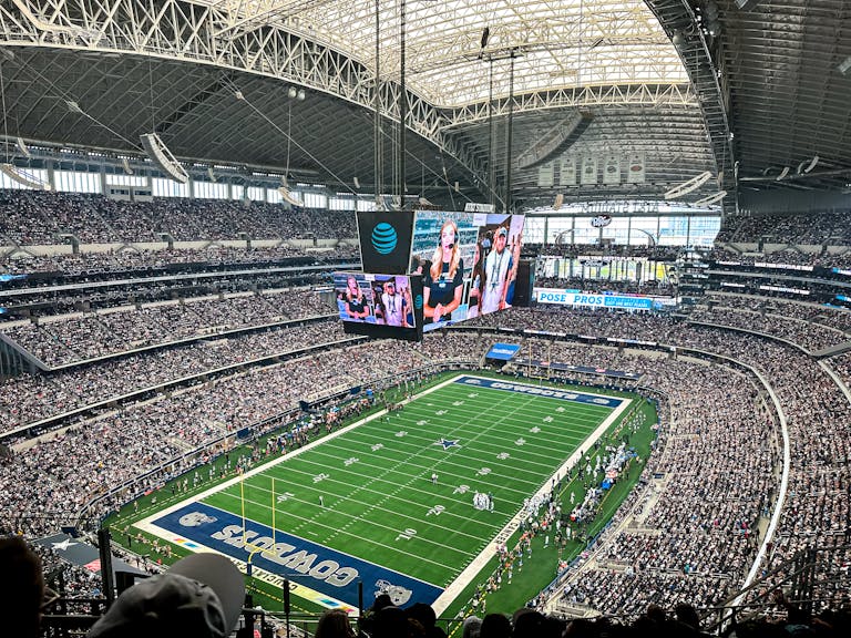A packed AT&T Stadium in Dallas Texas, showcasing a thrilling football game with enthusiastic fans.