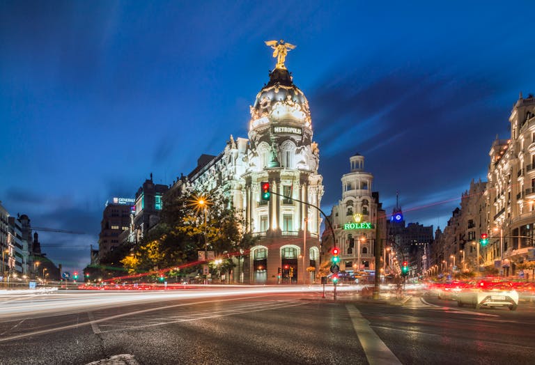 A stunning night view of the Metropolis Building with light trails and vibrant city lights in Madrid.