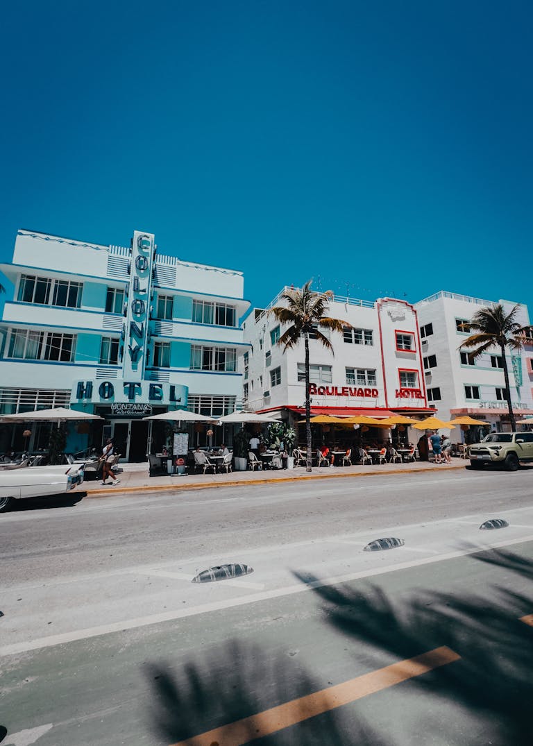 Colorful scene capturing Miami Beach's historic Ocean Drive with palm-lined street and iconic Art Deco hotels.