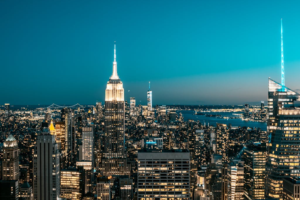 Dazzling New York City skyline glowing at night with iconic skyscrapers and vivid lights.