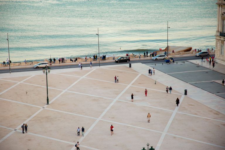 High angle citizens strolling on vast public square near rippling river located in coastal city in twilight