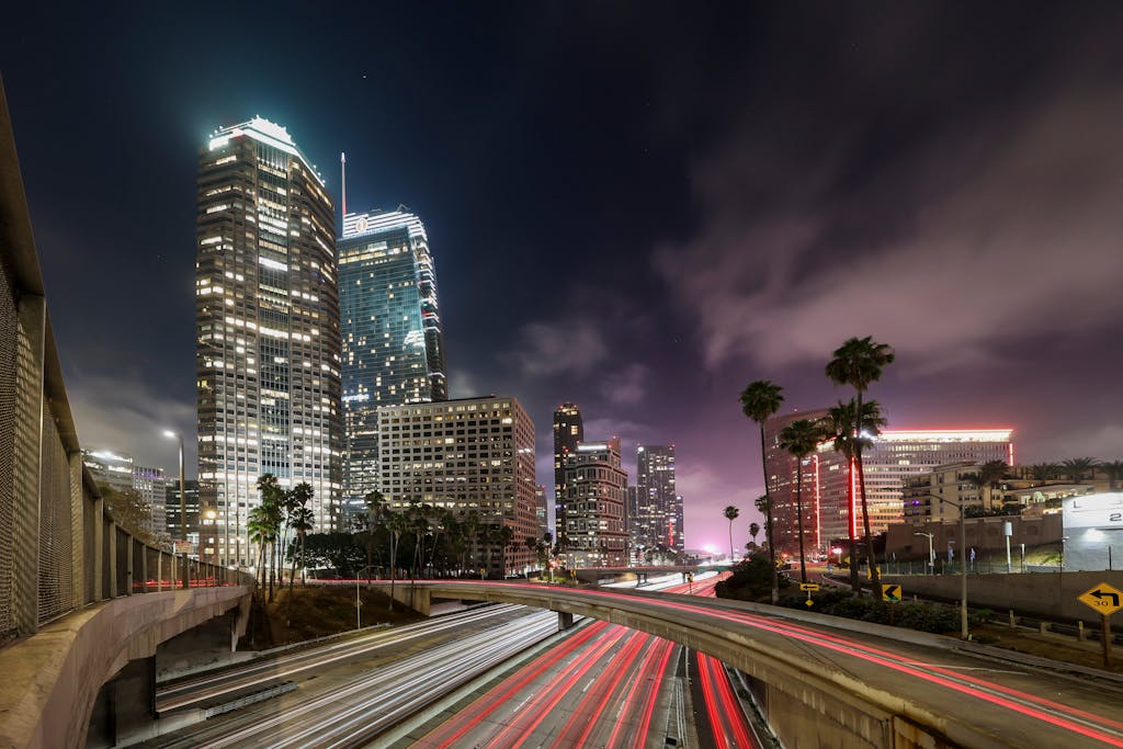 Stunning long-exposure night shot of Los Angeles skyline with illuminated highways and towering buildings.